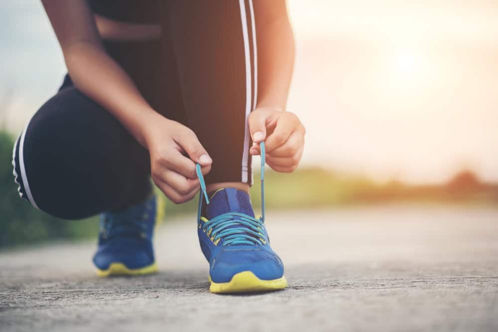 close up shoes female runner tying her shoes for a jogging